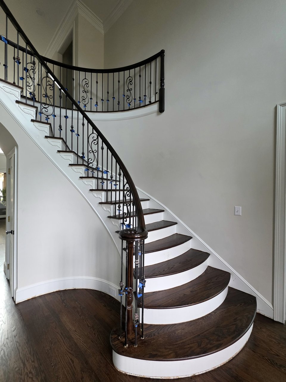 Curved wood staircase with white risers and dark handrail