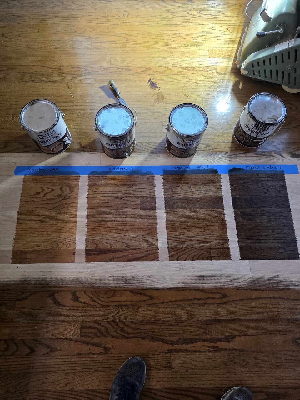 Several stain samples taped out on a wood floor